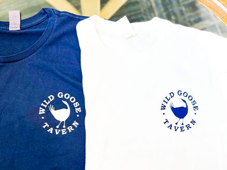 The image shows two T-shirts, one blue and one white, both with a logo that reads 