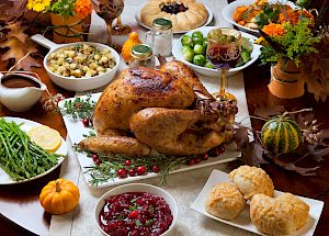 A Thanksgiving feast with roasted turkey, cranberry sauce, stuffing, green beans, biscuits, and assorted seasonal decorations end the sentence.