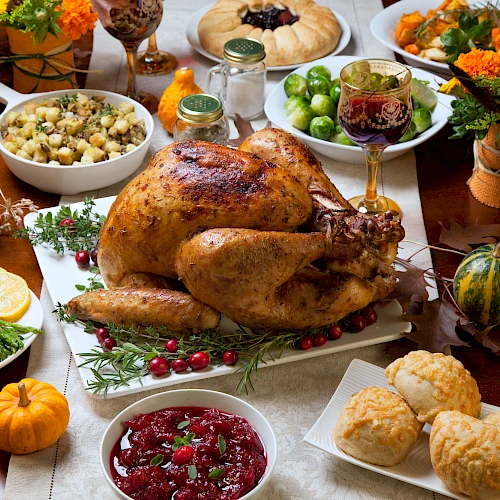 A Thanksgiving feast with roasted turkey, cranberry sauce, stuffing, green beans, biscuits, and assorted seasonal decorations end the sentence.